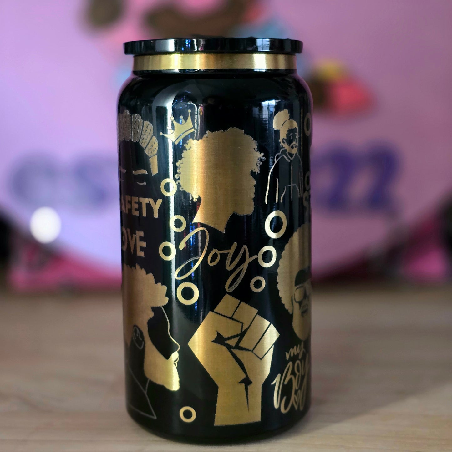 Black cup with gold graphics and text on a blurred background